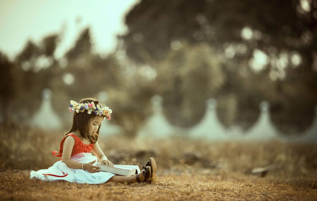 Criança sentada ao ar livre lendo um livro, simbolizando proteção, cuidado parental e os direitos da criança em casos de guarda compartilhada e pensão alimentícia.