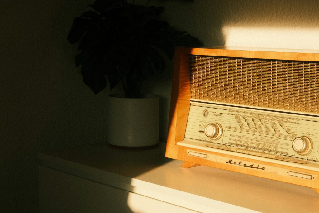 Rádio vintage em um ambiente acolhedor de casa de repouso, iluminado pela luz natural, com uma planta ao fundo.