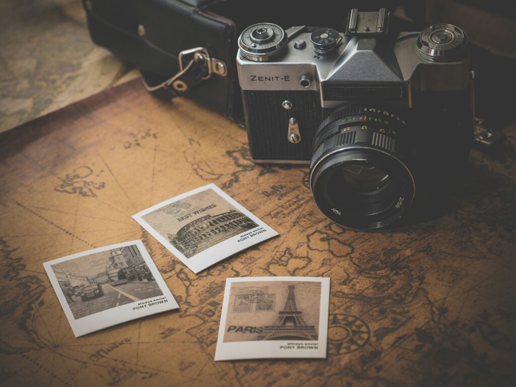 Câmera fotográfica antiga Zenit-E sobre um mapa envelhecido, ao lado de fotos de Paris, Roma e Londres, evocando encontros entre países e o tema do casamento internacional.