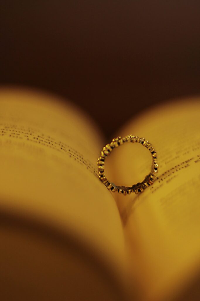 Anel dourado apoiado nas páginas abertas de um livro antigo, com iluminação em tons de âmbar, simbolizando o fim de um casamento e o tema do divórcio internacional.